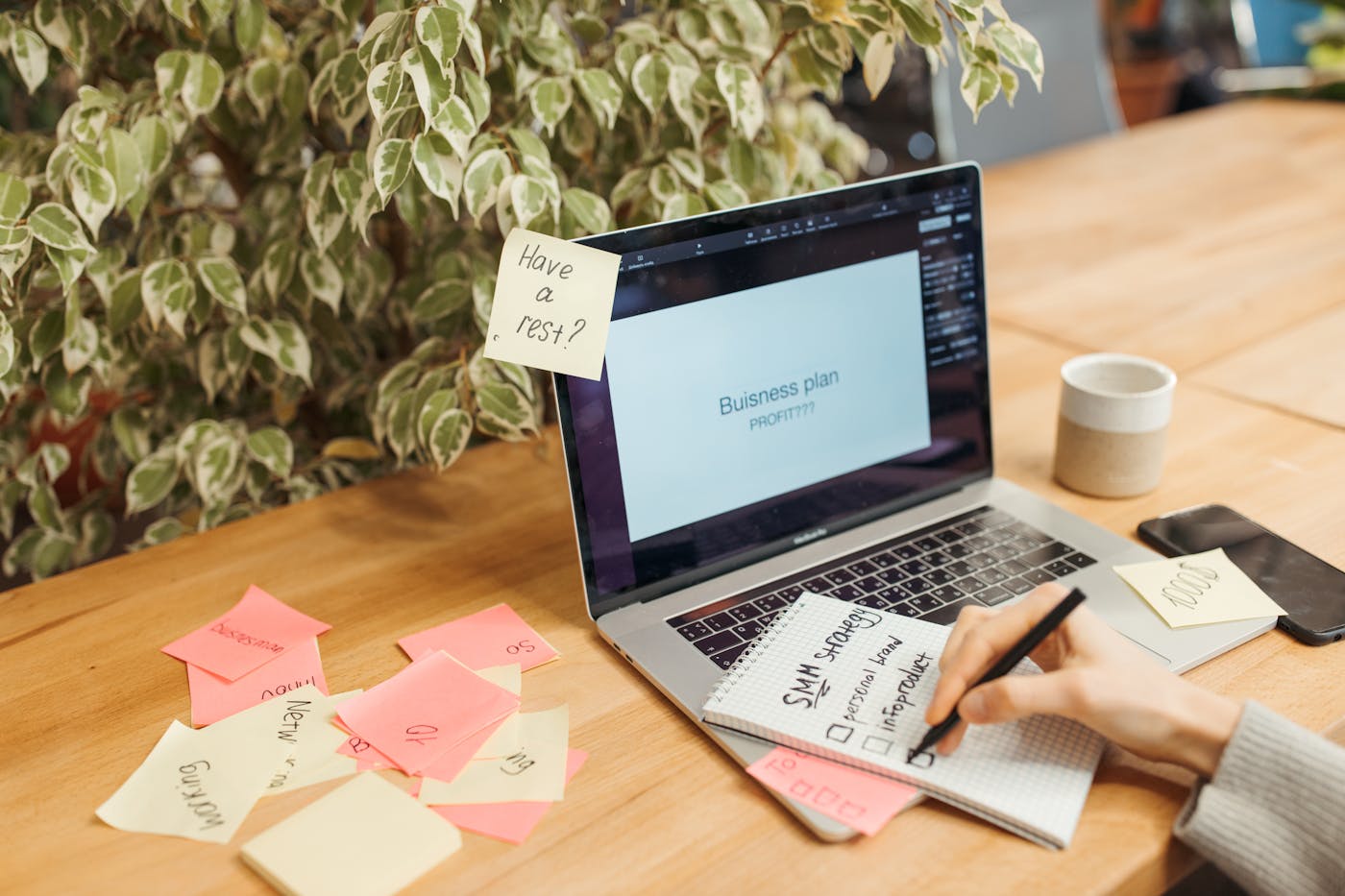A desk with a laptop, sticky notes, and a notepad prepared for planning an email campaign sequence
